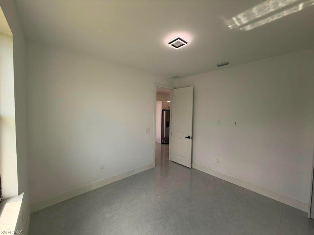 Bright room featuring light grey tile flooring, white baseboards, and a modern flush-mount ceiling light