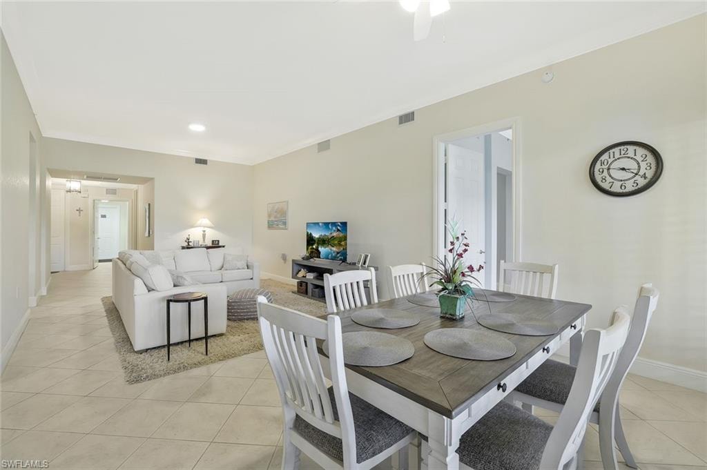Dining room featuring light tile patterned floors, crown molding, and ceiling fan
