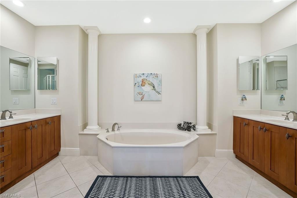 Bathroom featuring decorative columns, tile patterned floors, two vanities, and recessed lighting