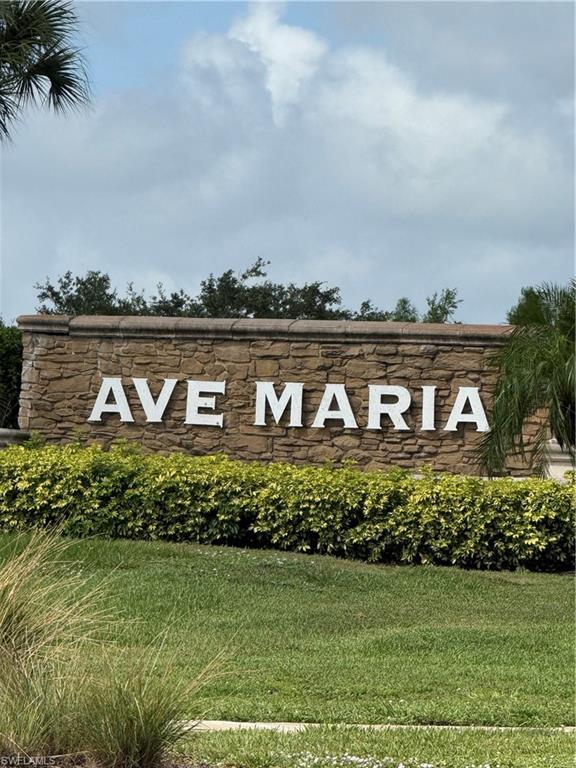 Stone-clad entrance monument featuring dimensional lettering, surrounded by manicured shrubbery and lush green lawns