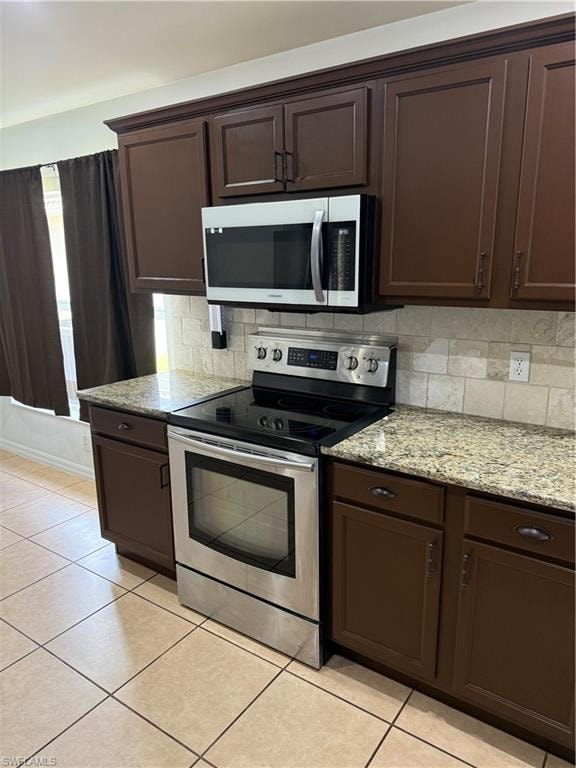 Kitchen featuring stainless steel range and microwave, granite countertops, tile backsplash, and dark wood cabinetry