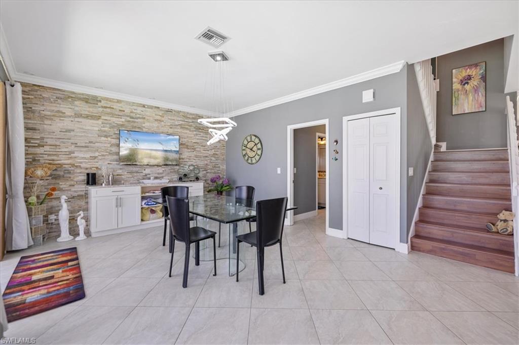 Dining space featuring visible vents, baseboards, ornamental molding, stairway, and light tile patterned floors
