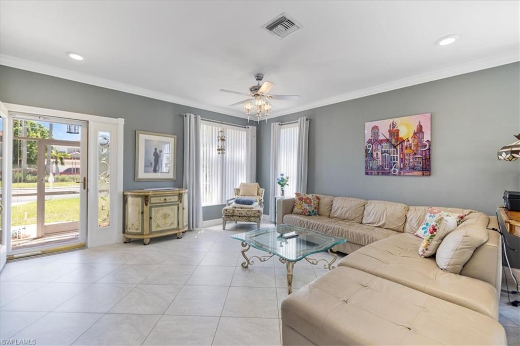 Living room featuring light tile patterned flooring, ornamental molding, visible vents, ceiling fan, and recessed lighting