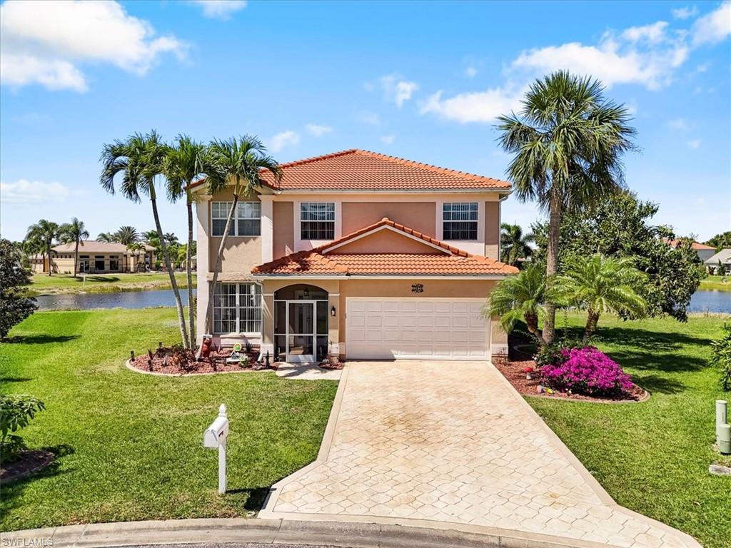 Mediterranean / spanish home featuring a front lawn, a tiled roof, decorative driveway, a water view, and a garage
