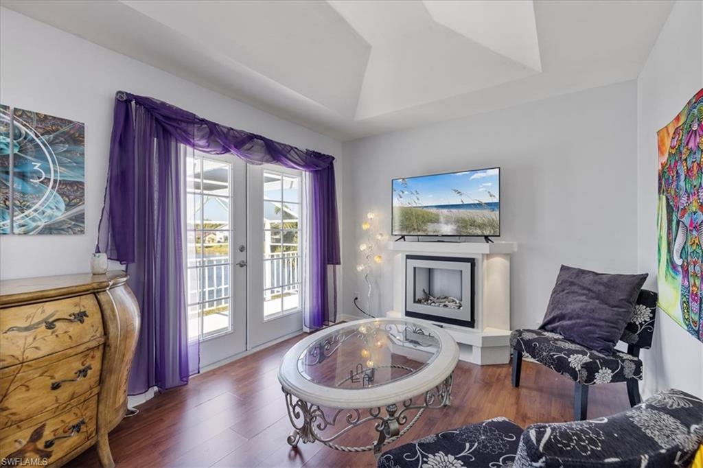 Sitting room with a tray ceiling, a fireplace, wood finished floors, and french doors