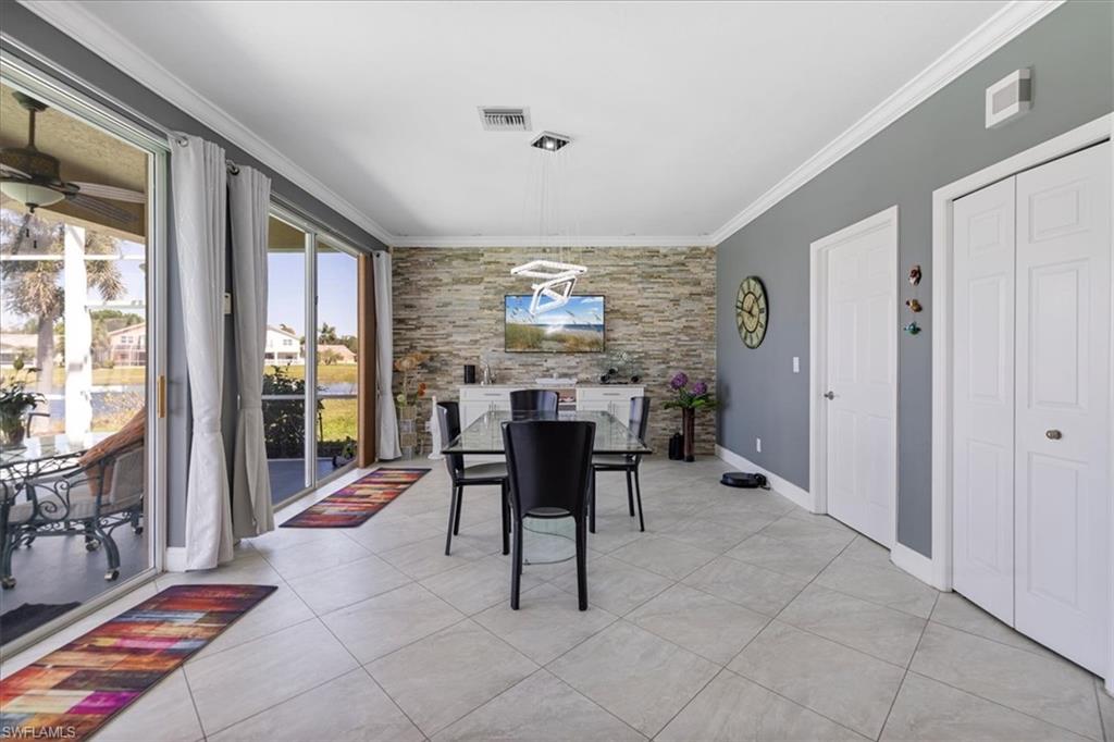 Dining room featuring light tile patterned floors, baseboards, visible vents, and crown molding
