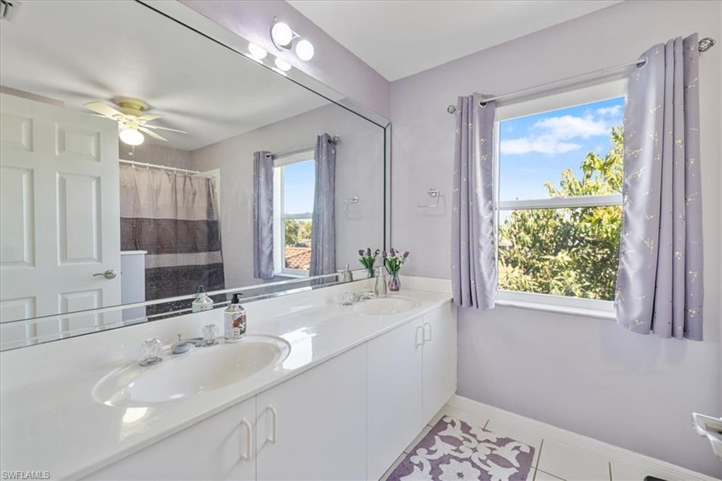 Bathroom with baseboards, double vanity, a sink, and tile patterned flooring