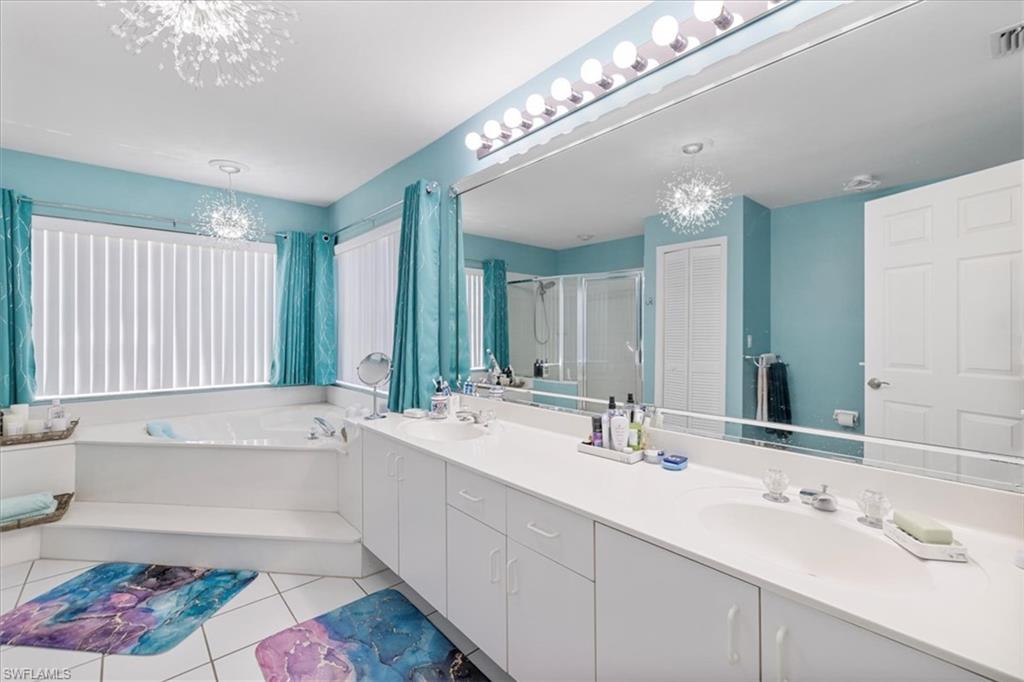 Full bathroom featuring a stall shower, tile patterned floors, double vanity, and a sink