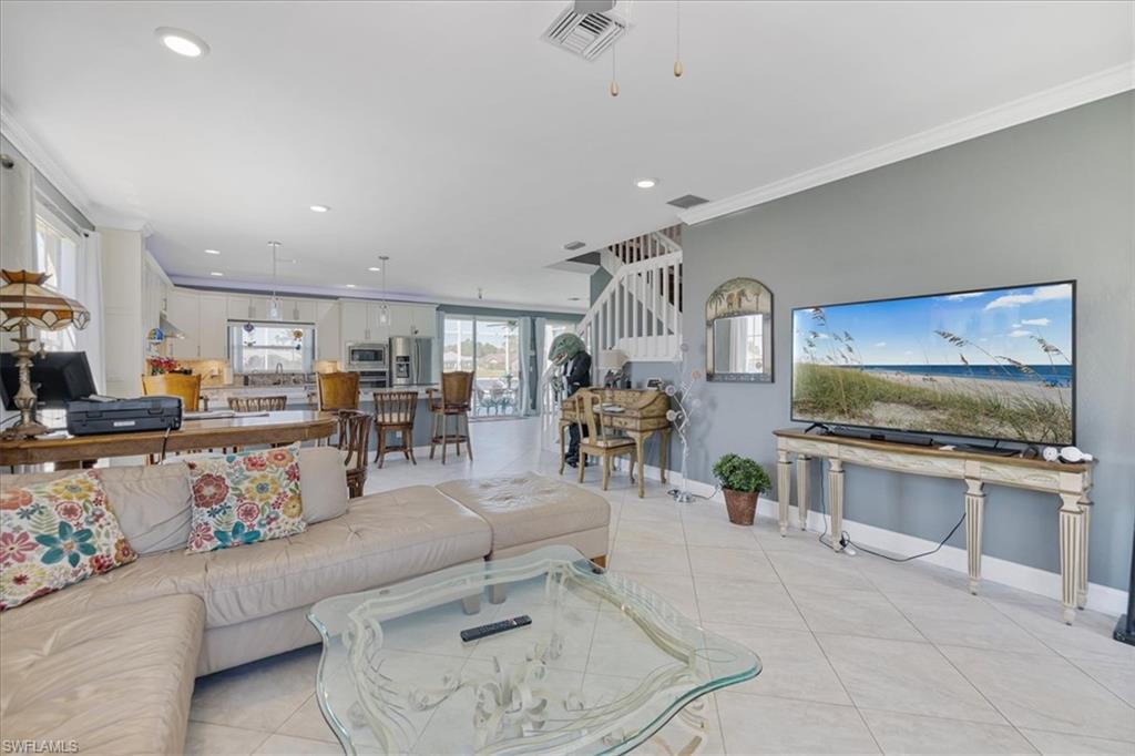 Living room with light tile patterned flooring, ornamental molding, recessed lighting, and visible vents