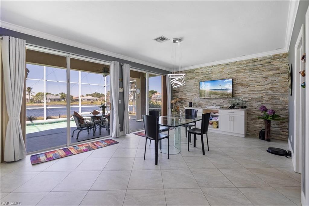 Dining room featuring light tile patterned floors, ornamental molding, a water view, and visible vents