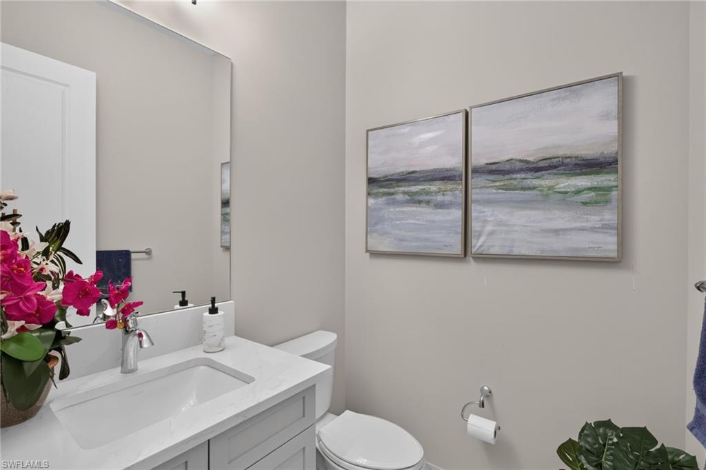 Bathroom featuring a light gray vanity with an integrated sink, polished chrome faucet, and a large wall-mounted mirror