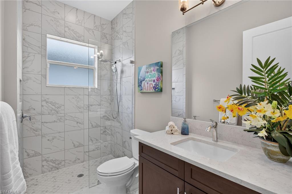 Spacious bathroom featuring a glass-enclosed shower with marble-look tile, a built-in window, and pebble-style flooring