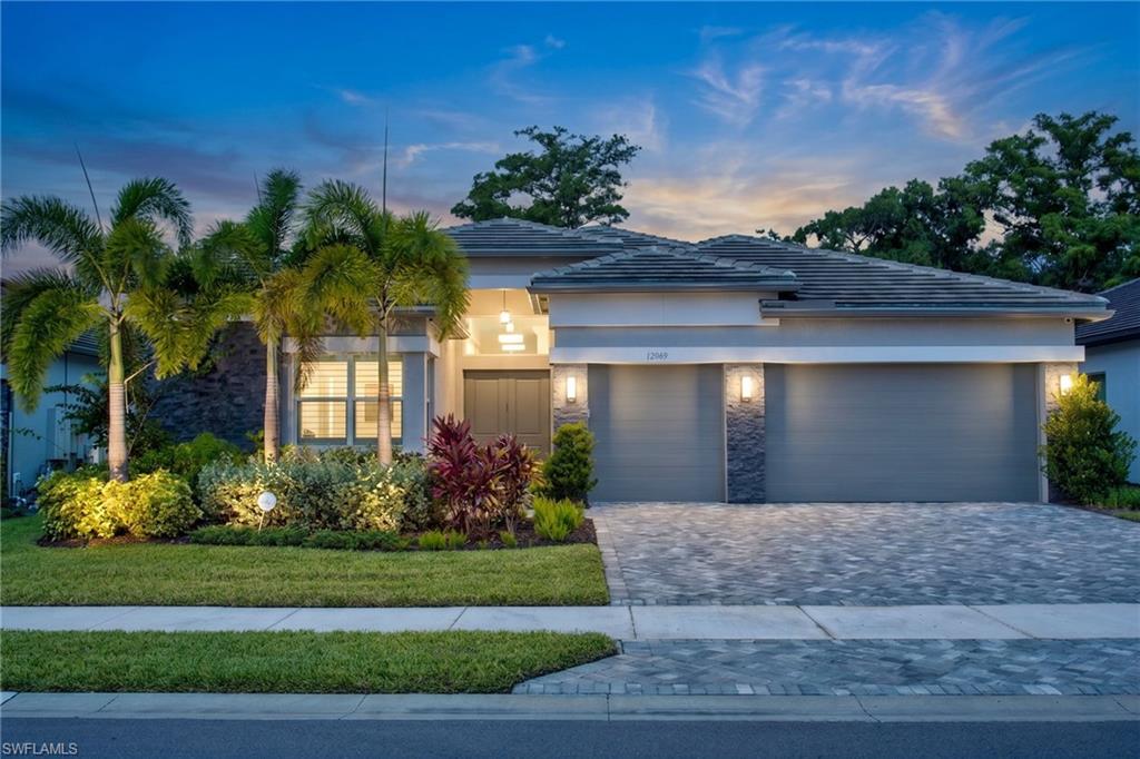 Contemporary exterior with a tile roof, paver driveway, and a two-car garage