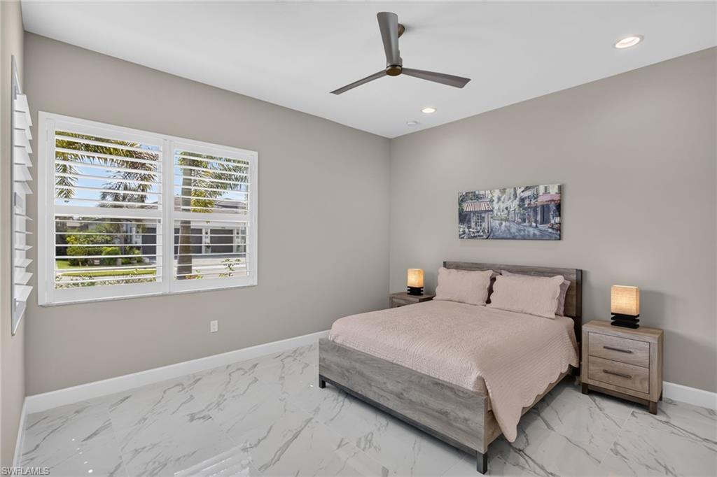Spacious room featuring white plantation shutters, recessed ceiling lighting, a modern ceiling fan, and large format marble-look tile flooring