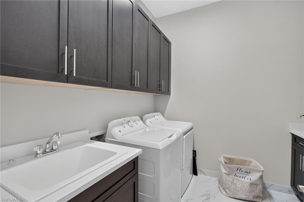 Laundry room featuring dark wood-finish cabinetry, a utility sink with a white countertop, and white tile flooring
