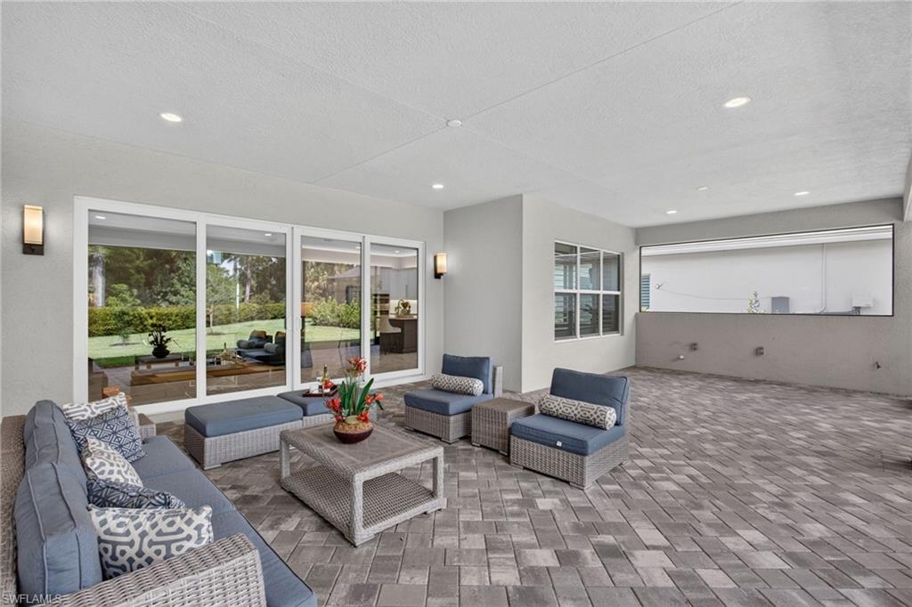 Spacious covered patio with a paver flooring, recessed lighting, and wall-mounted sconces