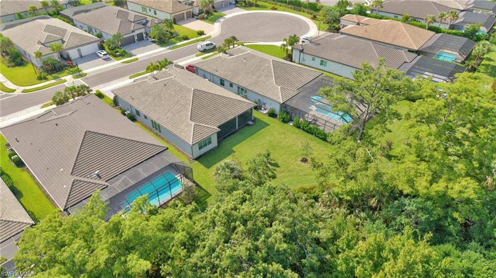 Aerial perspective of a neighborhood featuring houses with screened pools and tiled roofs