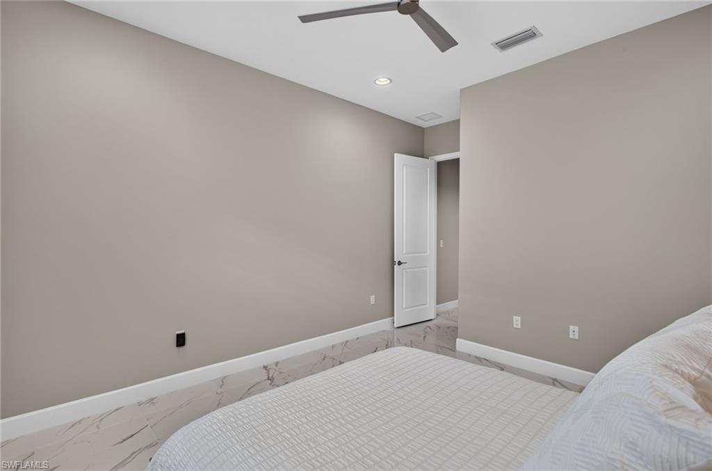 Spacious room featuring light gray walls, large format tile flooring, and a modern ceiling fan