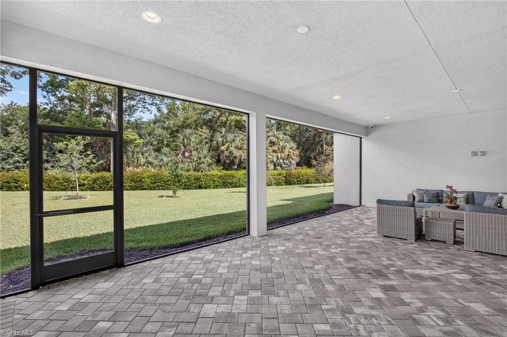 Screened patio featuring gray paver flooring, recessed lighting, and a white stucco wall
