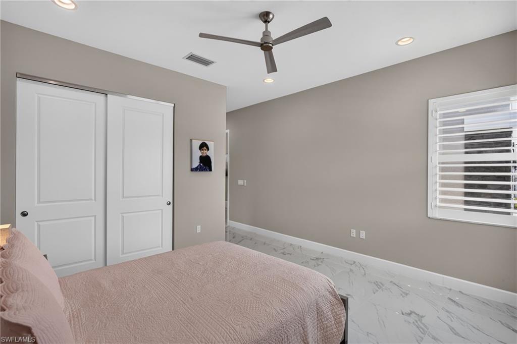 Spacious room featuring white panel sliding closet doors, a contemporary ceiling fan, and recessed lighting