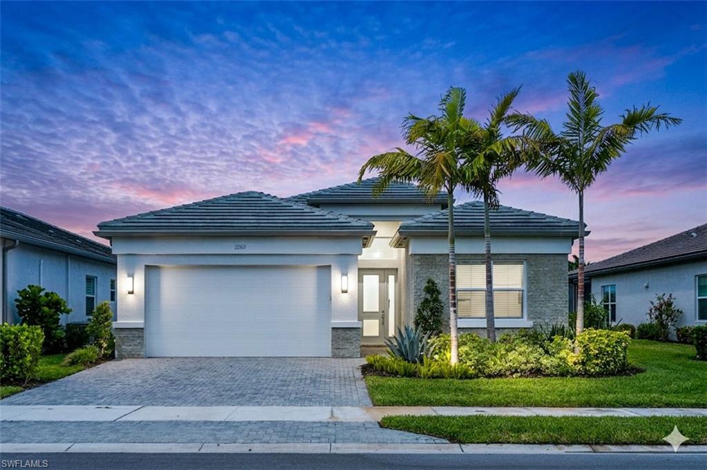 Modern facade featuring a tile roof, stone accents, and a paver driveway