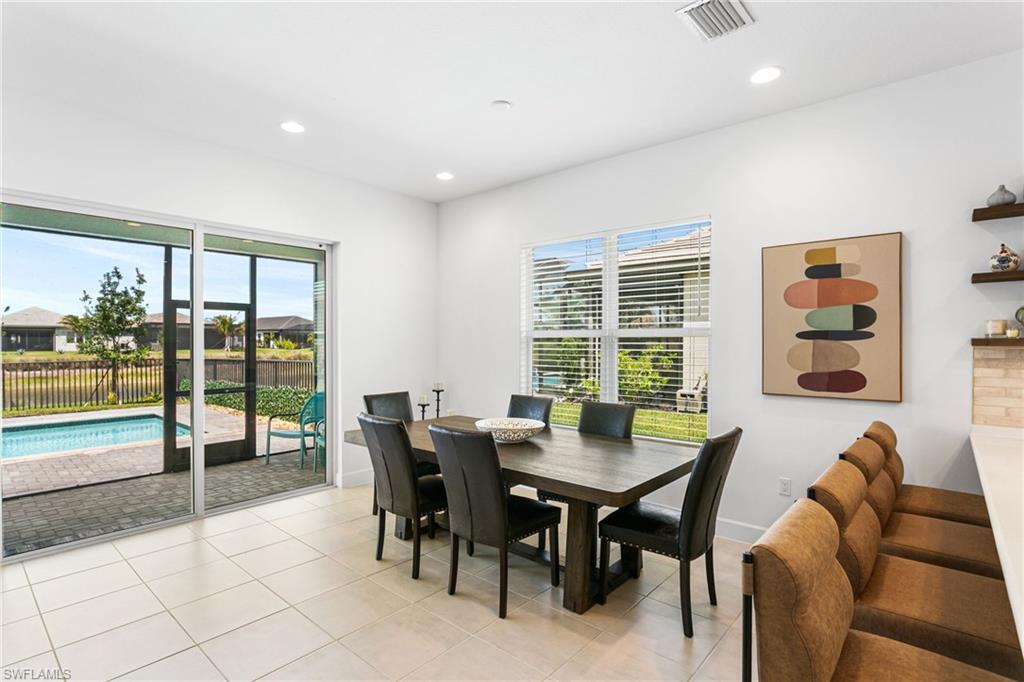 Tile flooring extending from the interior to the screened lanai, featuring a rectangular swimming pool and a water view