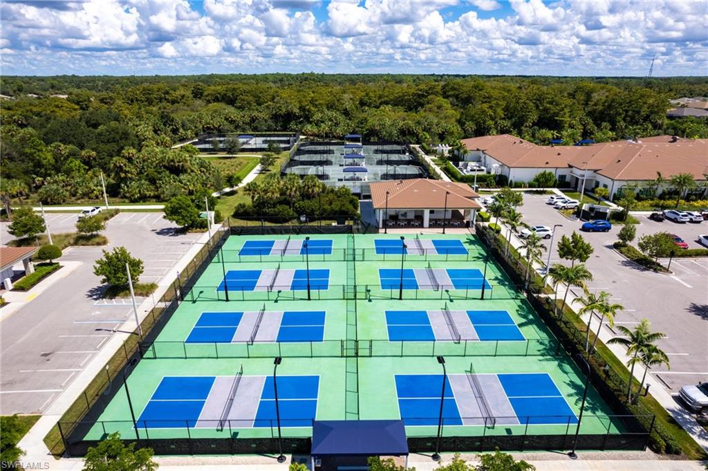Multiple outdoor pickleball courts with perimeter fencing, a covered pavilion, and surrounding parking areas