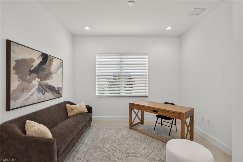 Bright interior space featuring a window with horizontal blinds, recessed lighting, and wood-finish flooring