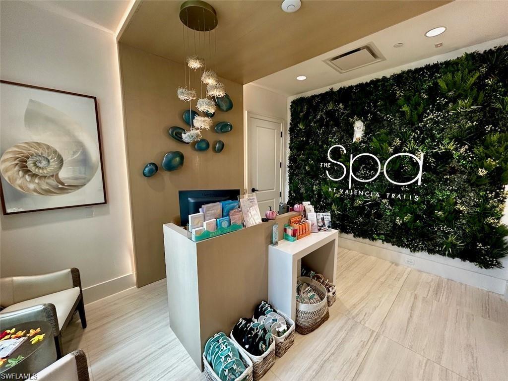 Feature wall with integrated greenery and signage, wood-finish flooring, custom wall art, recessed lighting, and a contemporary chandelier