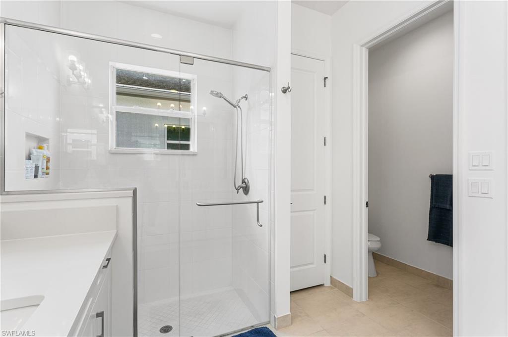 Glass-enclosed shower featuring a built-in niche, window, and chrome fixtures