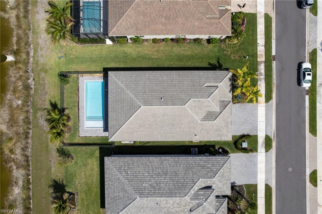 Aerial perspective showcasing the property's exterior, including a swimming pool with integrated steps, a landscaped yard, and a paved driveway