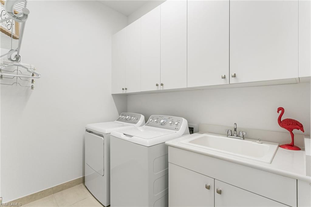 Dedicated laundry area featuring white cabinetry, a utility sink with stainless steel faucet, and tile flooring