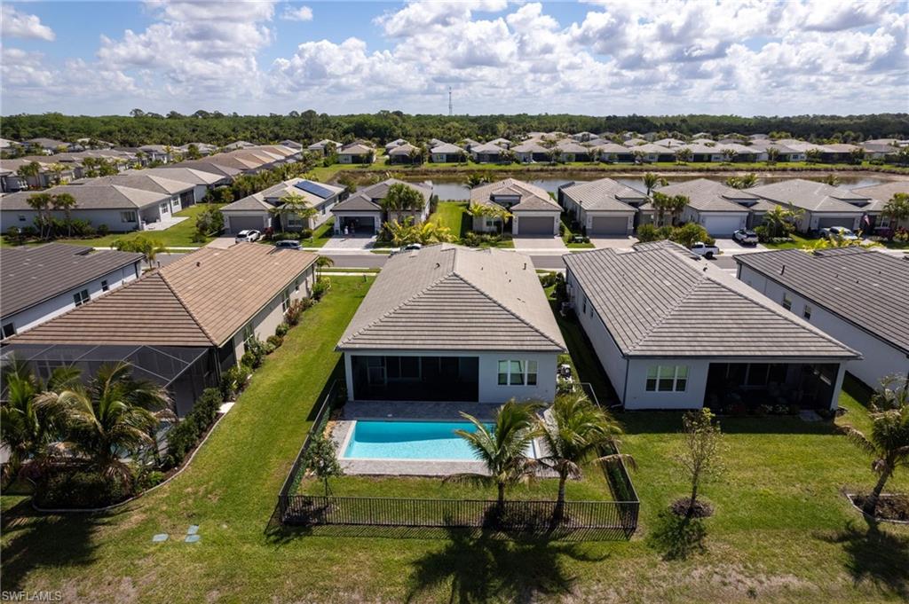 Rear exterior featuring a screened-in swimming pool, paved pool deck, and a fenced yard with mature palm trees