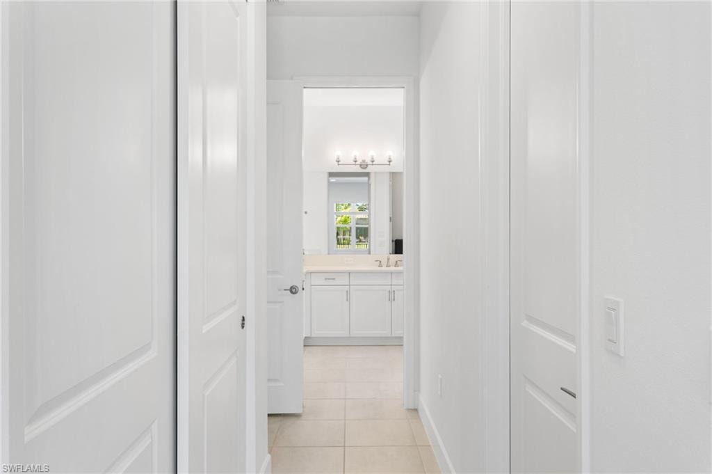 Hallway with light-toned tile flooring and white paneled doors