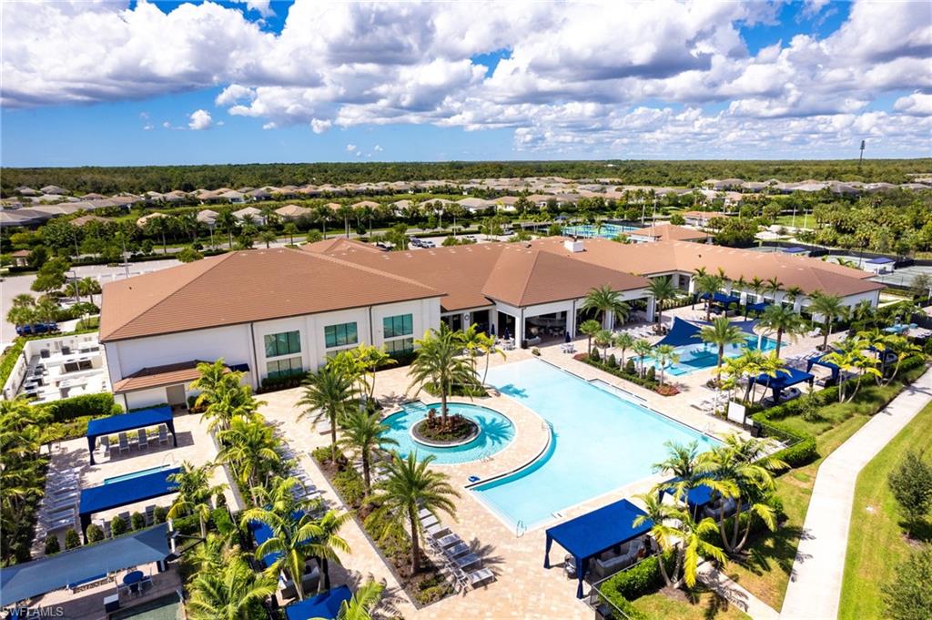 Expansive outdoor amenity area featuring multiple swimming pools, extensive patio decking, and established landscaping