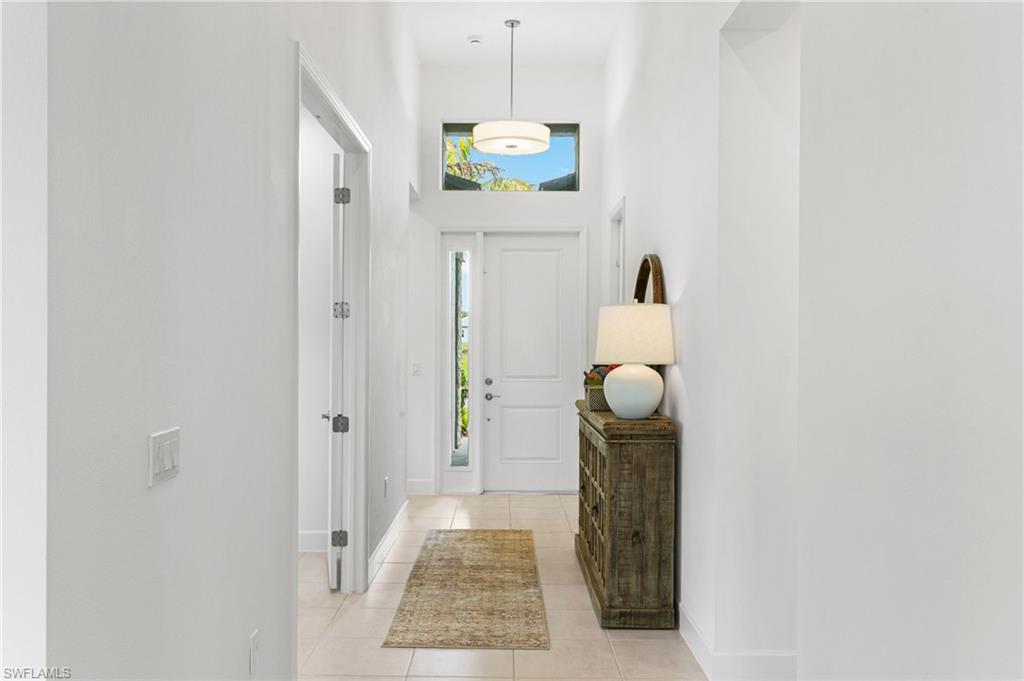 Entryway featuring a white paneled door with sidelight, transom window, and a drum pendant light