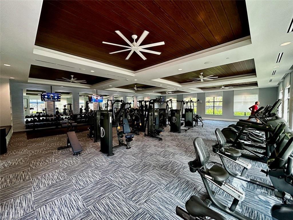 Spacious fitness center featuring varied exercise equipment, patterned carpet flooring, recessed lighting, and ceiling fans