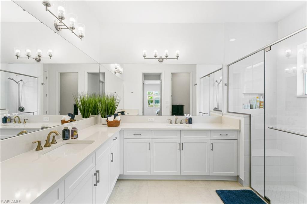 Spacious bathroom featuring an extended vanity with two undermount sinks, white cabinetry, and a light-colored countertop