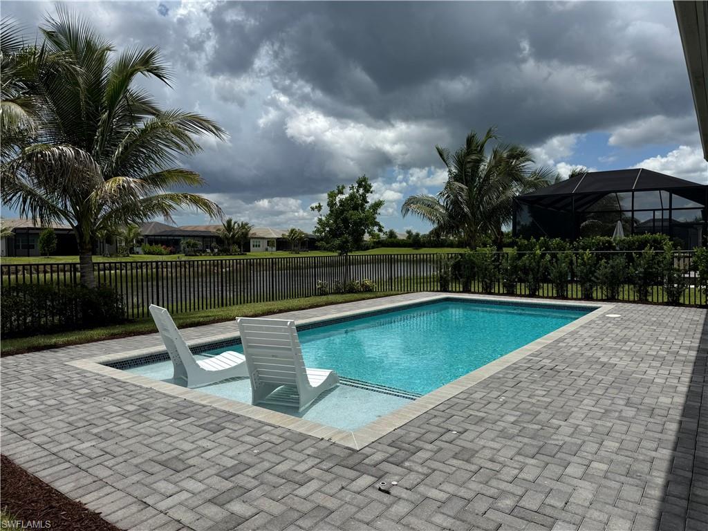 Rectangular swimming pool featuring an in-pool sun shelf and surrounding paver patio