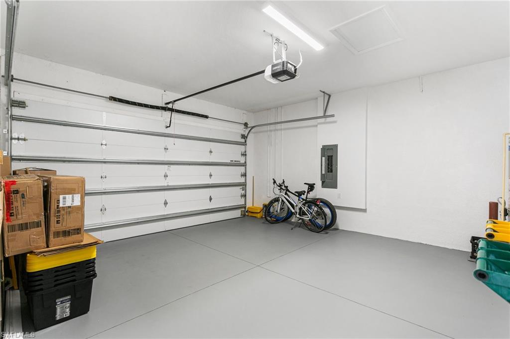 Spacious garage featuring a light gray epoxy floor coating, white overhead garage door, and an automatic garage door opener