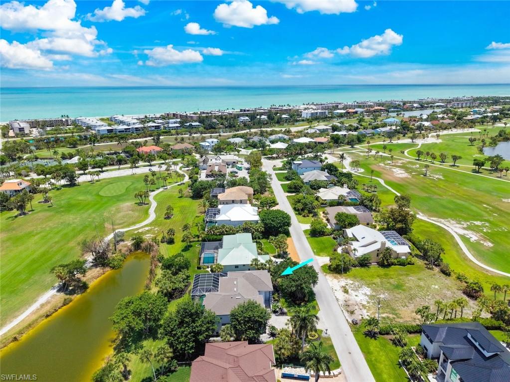 Aerial perspective featuring an extensive golf course, multiple residences, and a body of water