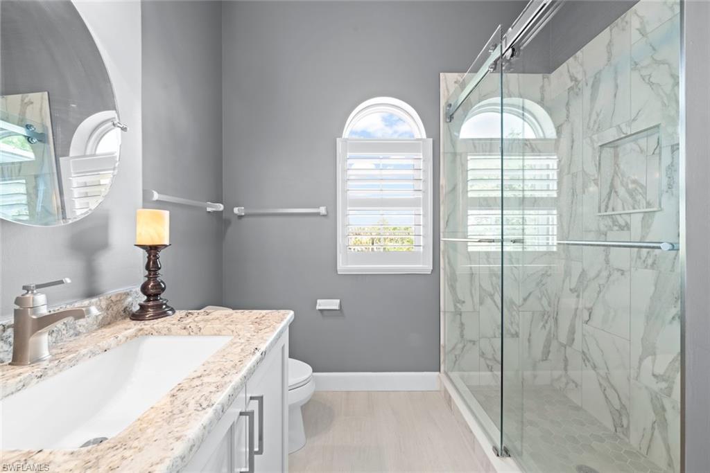 Bathroom featuring a glass-enclosed shower with marble-look wall tiles and a built-in niche