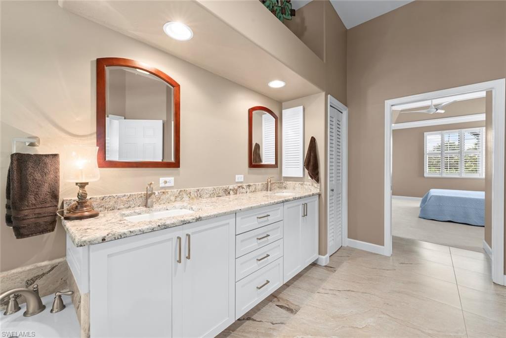Bathroom featuring a dual vanity with a light-colored countertop, white cabinetry with brushed nickel hardware, and two framed mirrors