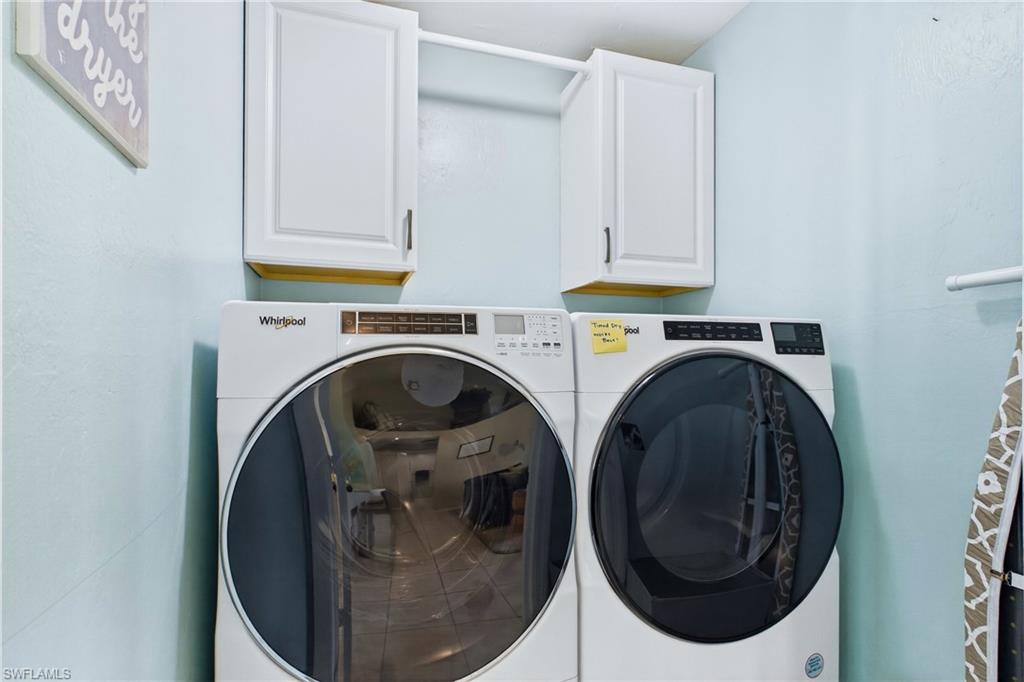 In home laundry room with upper cabinets and hanging shelf.
