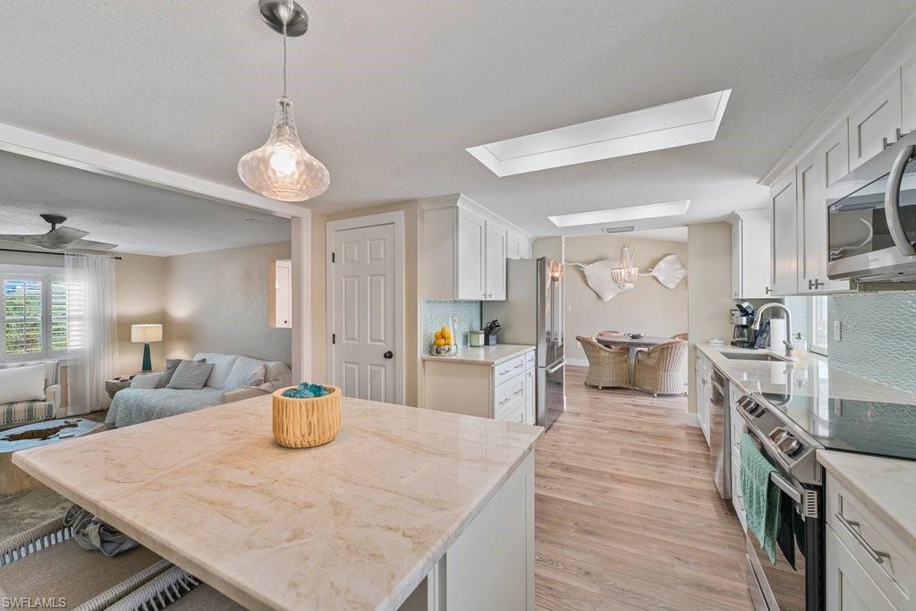 Central kitchen island with stone countertop, accompanied by recessed lighting and skylights