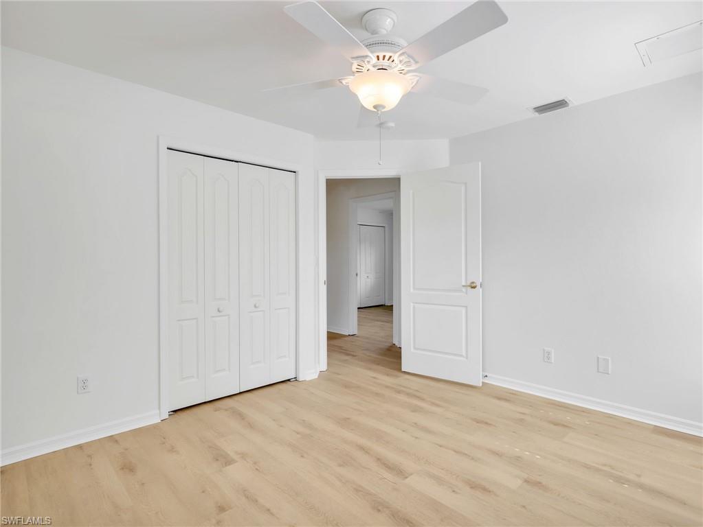 Room featuring wood-finish flooring, white walls, and a ceiling fan with integrated lighting