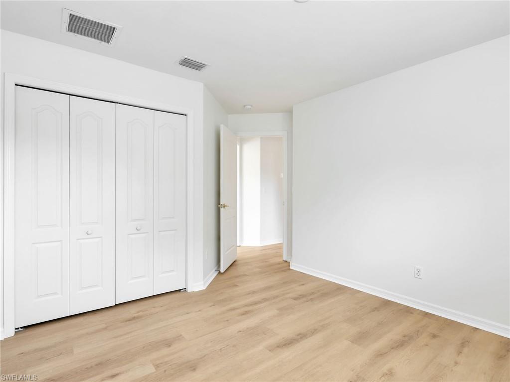 Room featuring wood-finish flooring, white baseboards, and a four-panel bi-fold closet door