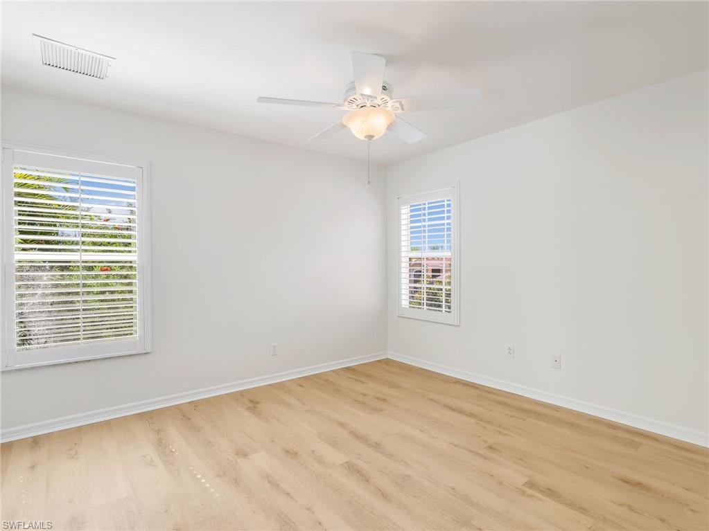 Bright room featuring wood-finish flooring, white walls, and a ceiling fan with integrated lighting