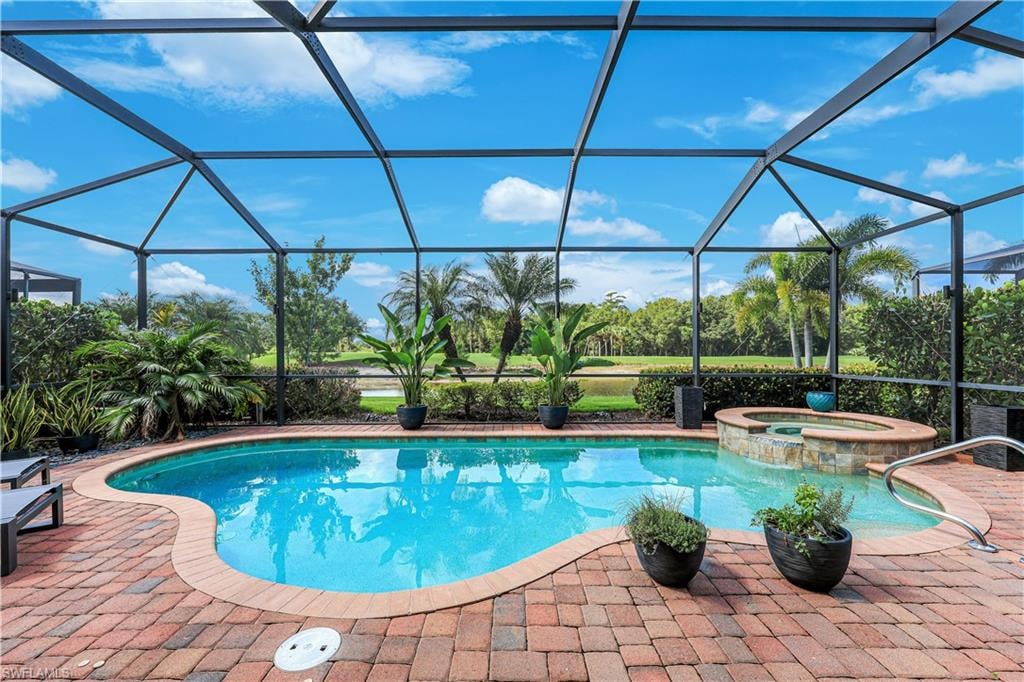 Screened outdoor pool area featuring a freeform pool, integrated spa with stone tile surround, and brick paver decking