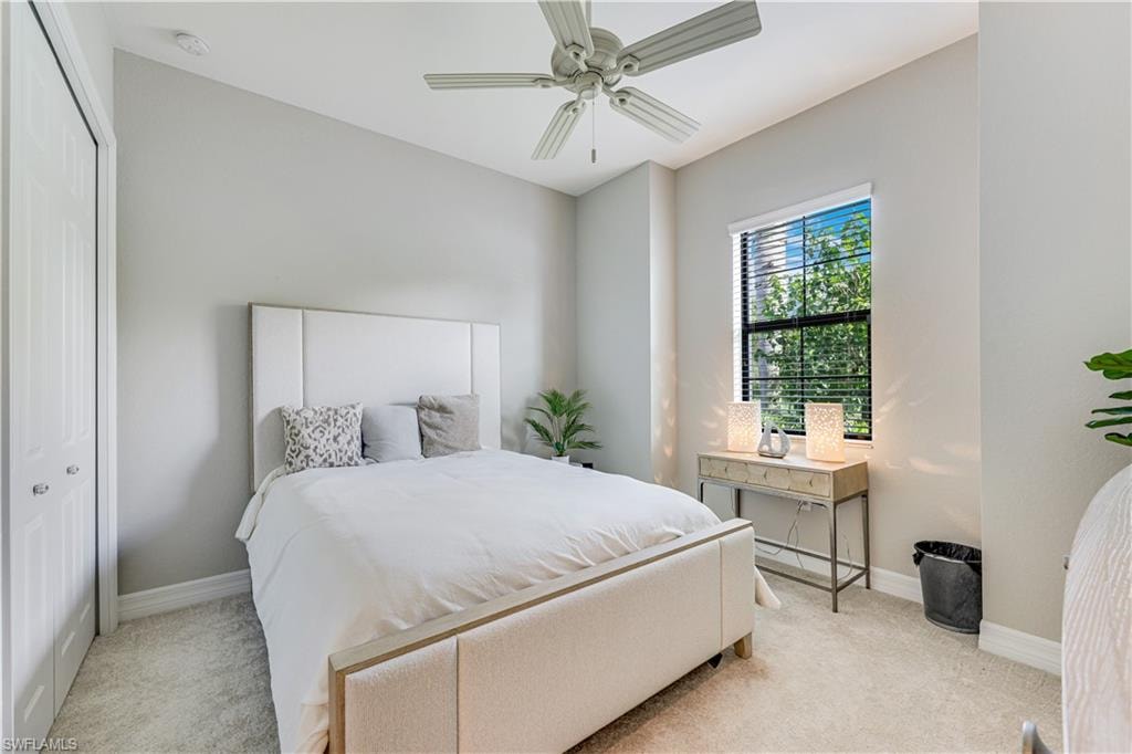 Carpeted room featuring a ceiling fan, a window with horizontal blinds, and a built-in closet with bi-fold doors